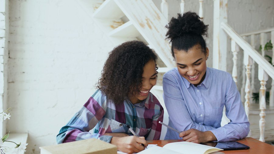 A pupil and tutor smiling together over her work