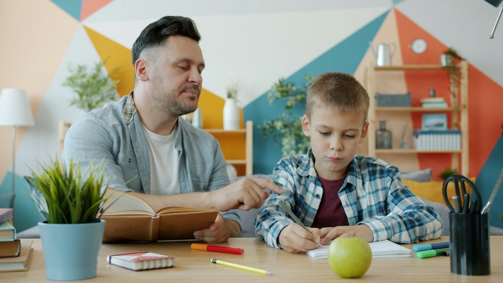 A parent helping his son with schoolwork at home