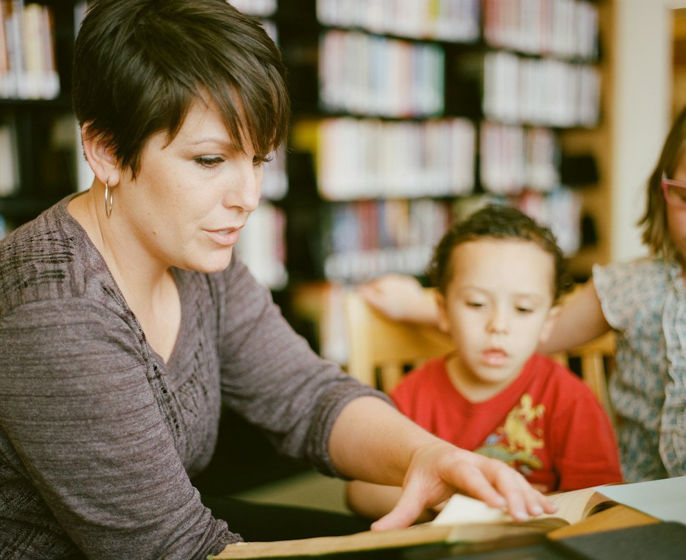 A tutor sitting beside a young pupil in a library